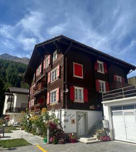 a building with red shuttered windows and a garage at Haus Chalet Arnika in Saas-Grund