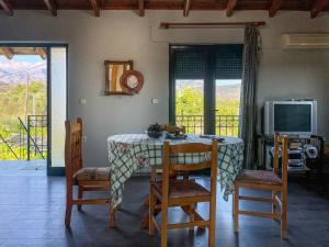 uma sala de jantar com uma mesa e cadeiras e uma televisão em Kavros House em Arménoi