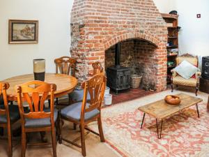 a living room with a table and a brick fireplace at Peggs Yard in Aylsham