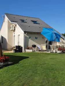 una casa blanca con un paraguas azul y un patio en gîte m et m, en Nébouzat