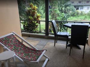 a balcony with two chairs and a table and a window at Riverside Guesthouse in Khao Lak