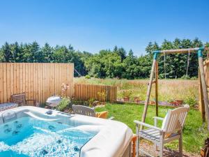 a hot tub in a backyard with chairs and a swing at Old Highwood - Piglet Cottage in Luppitt