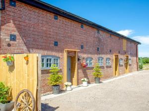 a brick building with potted plants in front of it at Old Highwood - Piglet Cottage in Luppitt