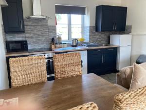 a kitchen with black cabinets and a wooden table with chairs at Martinmas Cottage in Flamborough