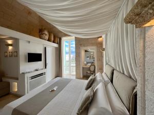 a bedroom with a bed and a couch and a television at Vittorio Emanuele Charming Suites in Monopoli