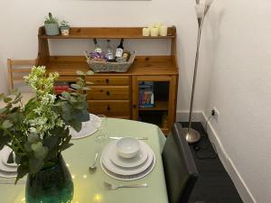 einem grünen Tisch mit Platten und einer Vase darauf in der Unterkunft Arden House in Comrie