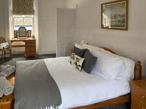 Schlafzimmer mit einem Bett mit weißer Bettwäsche und Kissen in der Unterkunft Arden House in Comrie