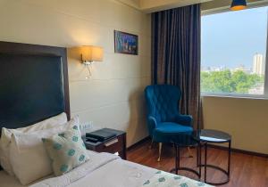 a hotel room with a bed and a chair and a window at Comfort Hotel Vista in Lucknow