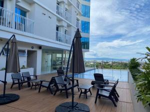 eine Terrasse mit Stühlen und Sonnenschirmen sowie einem Pool in der Unterkunft Inspiria Davao in Davao City