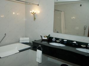a bathroom with a sink, mirror, and bathtub at Avari Lahore Hotel in Lahore