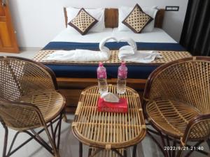 Habitación con 1 cama con sillas y 2 botellas de agua en una mesa. en Devi Kripa Residency en Varkala