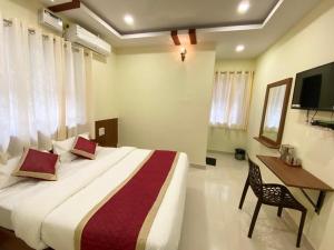 波尔沃林Prabhuvihar Residency的一间卧室，配有一张床、一张书桌和一台电视