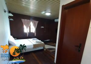 a bedroom with a white bed and a window at GLOBAL IKHWAN RESORT in Kuah