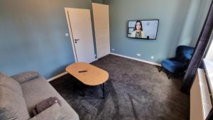 a living room with a couch and a table and a tv at Apartamenty Chorzów obok Parku Śląskiego in Chorzów
