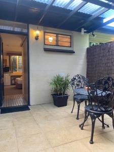 a patio with two chairs and a table and a window at Tallow Beach Motel in Byron Bay