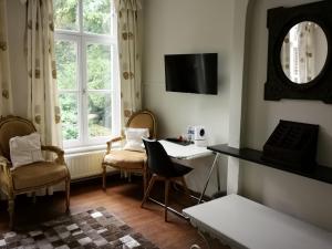 ein Wohnzimmer mit einem Tisch, Stühlen und einem Spiegel in der Unterkunft Eremyten Hof in Evergem