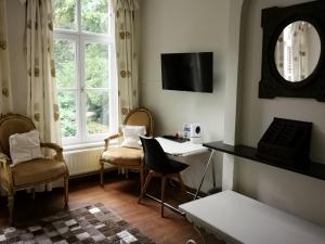 a living room with a table and chairs and a mirror at Eremyten Hof in Evergem