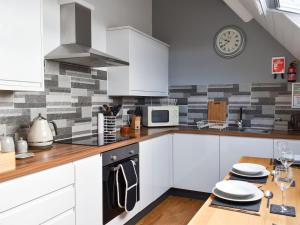 a kitchen with white cabinets and a clock on the wall at Waterwynch in Criccieth