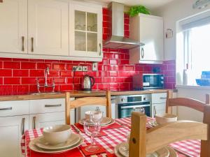 a kitchen with a table and a red brick wall at The Captains Cabin in Brixham