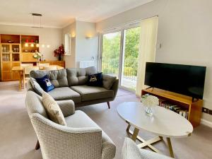 sala de estar con sofá, TV y mesa en Leighwood Cottage, en Paignton