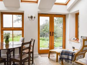 a dining room with a table and chairs and windows at Nant Y Crogwyn in Penmachno