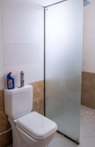 a bathroom with a toilet and a glass shower stall at Leomilo Holidays in Diani Beach