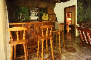 uma cozinha com um bar com bancos de madeira e uma guitarra em Omusee Self Catering em Baie Sainte Anne