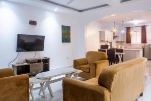 ein Wohnzimmer mit Stühlen, einem TV und einem Tisch in der Unterkunft Leomilo Holidays in Diani Beach