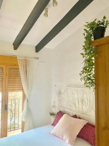 Preciosa villa en el corazón de Gandia في غانديا: غرفة نوم بسرير ابيض عليها نبات