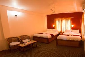a hotel room with two beds and a table and chairs at Hotel River Park in Pokhara