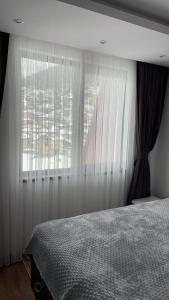 a bedroom with a bed and a window with curtains at ORION APARTMENTS in Chepelare