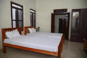 um quarto com 2 camas com lençóis brancos e janelas em Bobbys Corner em Alappuzha