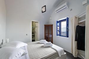 Cette chambre blanche dispose de deux lits et d'une fenêtre. dans l'établissement Domus Solis Luxury Villa, à Oia