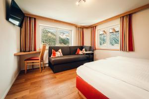 a hotel room with a bed and a couch at Ferienhotel Almajur in Mittelberg