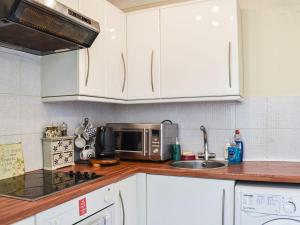 a kitchen with white cabinets and a microwave at Ace Lodge in Hoddesdon