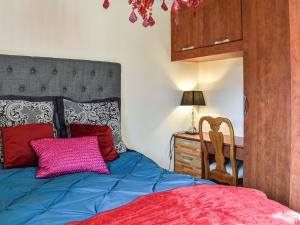 um quarto com uma cama azul e uma almofada rosa em Ace Lodge em Hoddesdon