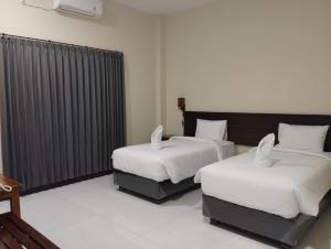 ラブハン・バジョにあるPalm bajo hotelの白いシーツが敷かれたベッドが2つある寝室