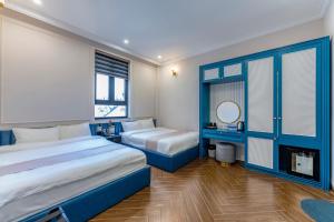 a hotel room with two beds and a mirror at Padona Hotel in Da Lat