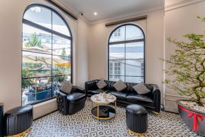 a living room with black leather furniture and windows at Padona Hotel in Da Lat