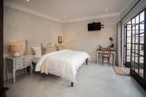 1 dormitorio con 1 cama y TV en la pared en Viewpoint Estate Guest House, en Haenertsburg