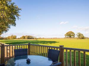 una mesa y sillas en una terraza con vistas a un campo en Cabin Hideaways, Glenfyne - Uk38362, en Mattishall
