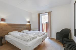 a bedroom with two beds and a chair and a window at Skagen Harbour Apartments in Skagen