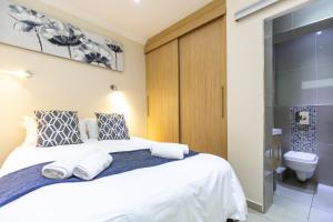 1 dormitorio con cama blanca y aseo en Perfect Beachfront Apartments, en Ciudad del Cabo