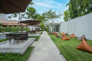 einen Garten mit Tischen, Stühlen und einem Sonnenschirm in der Unterkunft Away Bangkok Riverside Kene in Bangkok