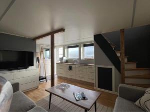 a living room with a couch and a tv and a table at Sauna House in Andenes