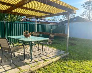 een patio met een tafel en stoelen onder een houten pergola bij Cosy guesthouse with private garden in Padstow