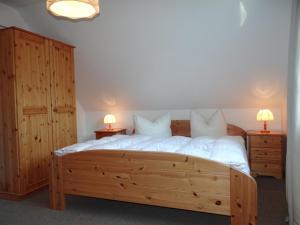 プレローにあるFerienanlage "Haus hinter den Dünen" Prerowのベッドルーム1室(大型木製ベッド1台、ランプ2つ付)