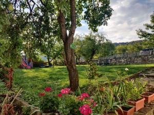 un parque con un árbol y flores en el césped en Старата къща - Трявна, en Tryavna