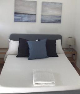 a white bed with three paintings on the wall at Ostia Bed and Beach in Lido di Ostia