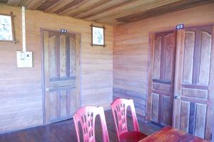 a dining room with two pink chairs and two doors at Song Lao Guesthouse in Thakhek